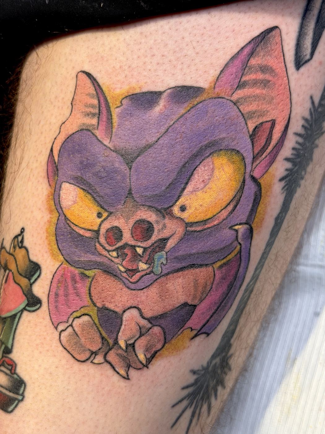 Purple and pink cartoon bat creature tattoo