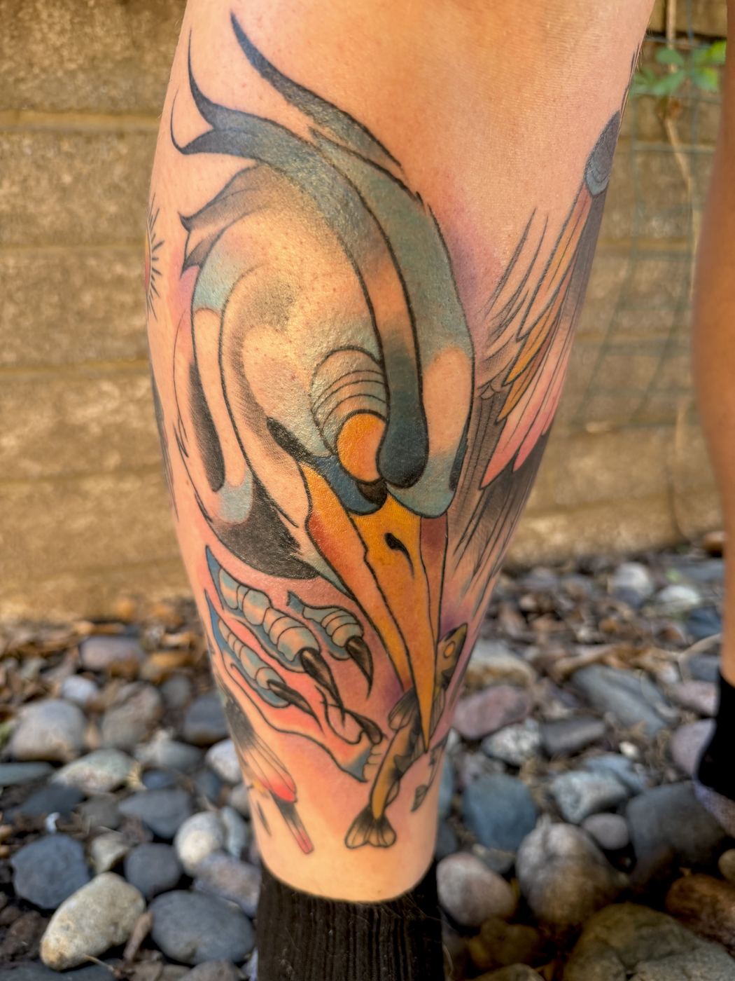 Colorful bird-dragon creature tattoo flying down the leg