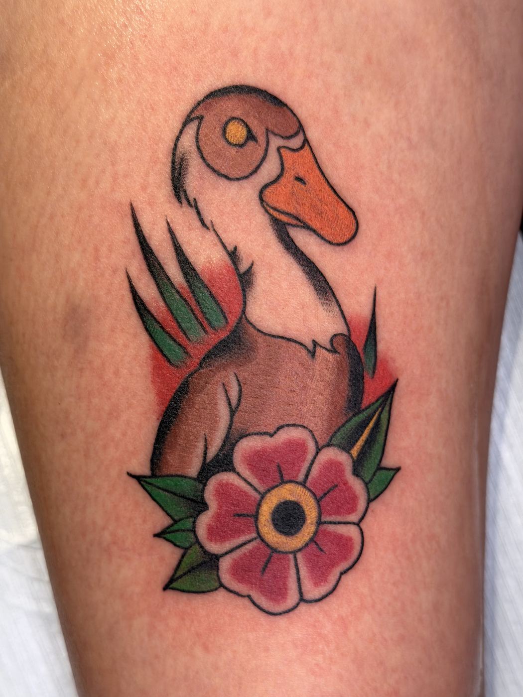Color tattoo of a duck head with a red flower