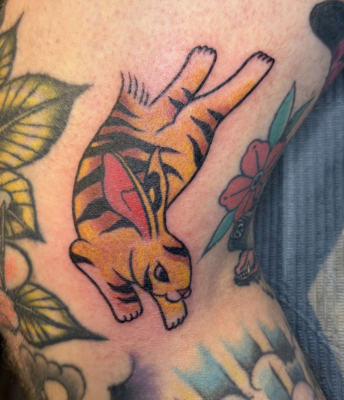 Tiger-striped rabbit tattoo leaping with a red flower