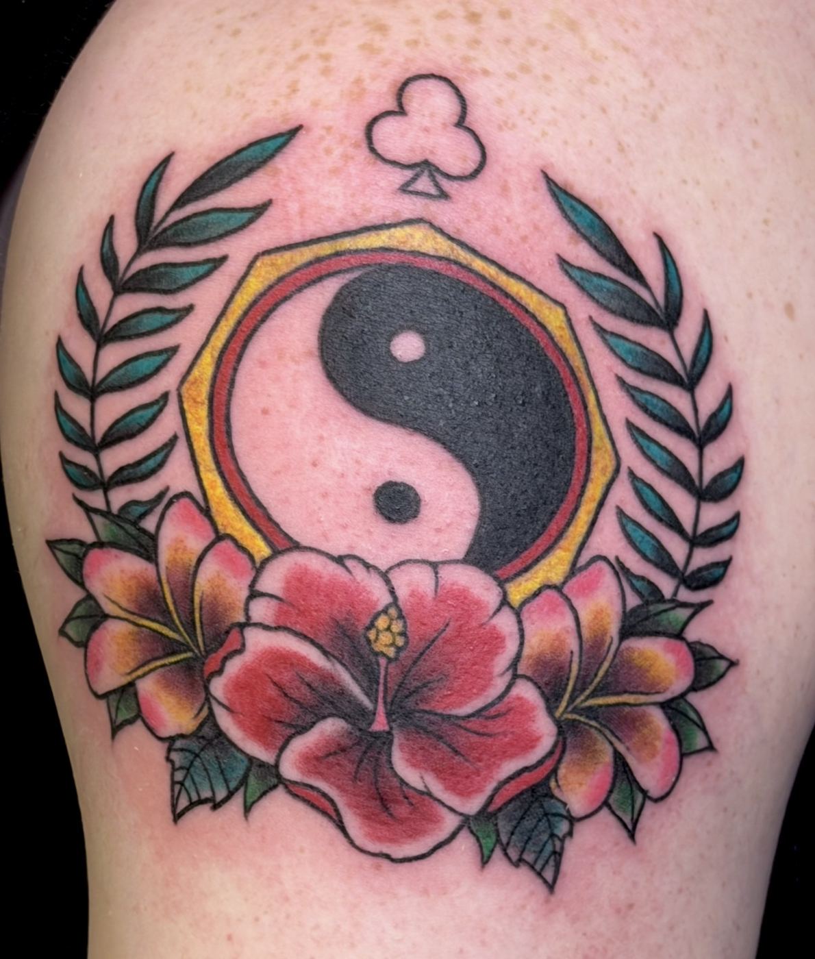 Yin yang medallion tattoo framed by hibiscus flowers